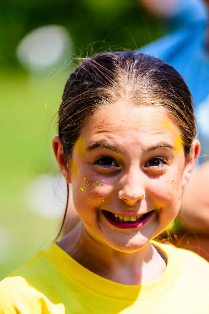 A girl in a bright yellow tee with wet hair, laughing straight at the camera.