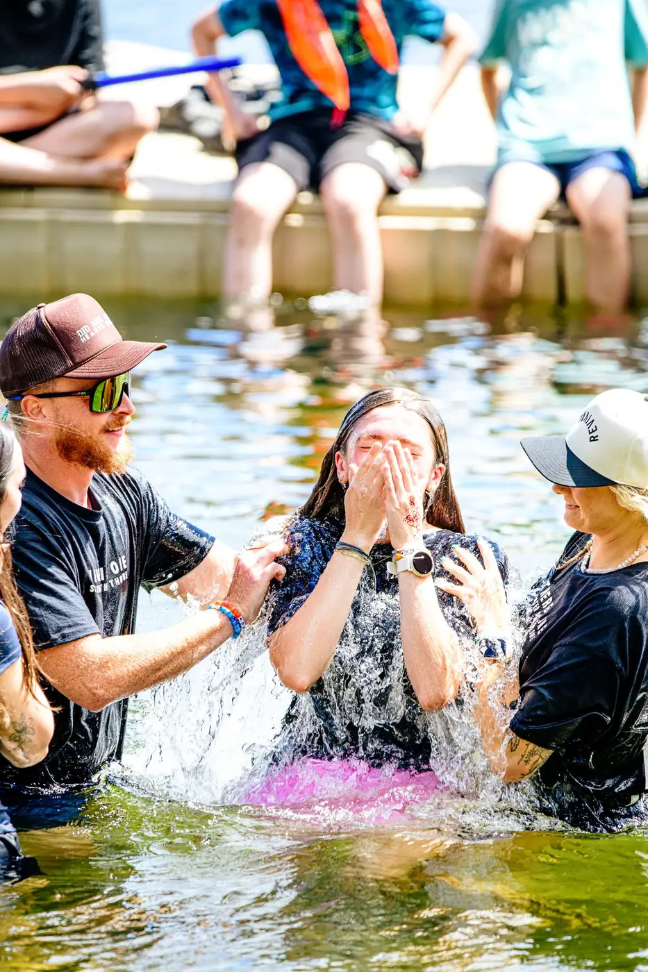 Surfacing: water exploding upward, hands pressed over her face, the pastor steadying her shoulder.