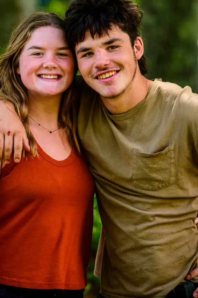 A boy and a girl with their arms around each other, both laughing.